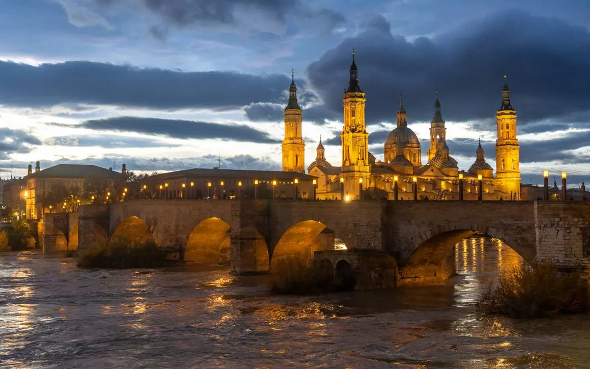 5. El puente de Piedra, viendo pasar los siglos
Una de las estampas m&aacute;s hermosas del Ebro a su paso por Zaragoza es la que forman los arcos del puente de Piedra, la elegante construcci&oacute;n que une ambas orillas desde tiempos medievales. Su fisonom&iacute;a actual parte de las obras iniciadas en 1401, aunque se sabe que en &eacute;poca musulmana ya hubo un puente en este lugar.
El pretil de San L&aacute;zaro, que tambi&eacute;n forma parte del conjunto monumental, data del siglo XVIII, y se levant&oacute; como muro de contenci&oacute;n. El puente fue testigo mudo de la invasi&oacute;n napole&oacute;nica, cuyas tropas volaron una de las arcadas en 1813. Hoy, por suerte, est&aacute; protegido como Bien de Inter&eacute;s Cultural, y nos regala magn&iacute;ficas vistas acompa&ntilde;adas de los gallardos leones que lo protegen.