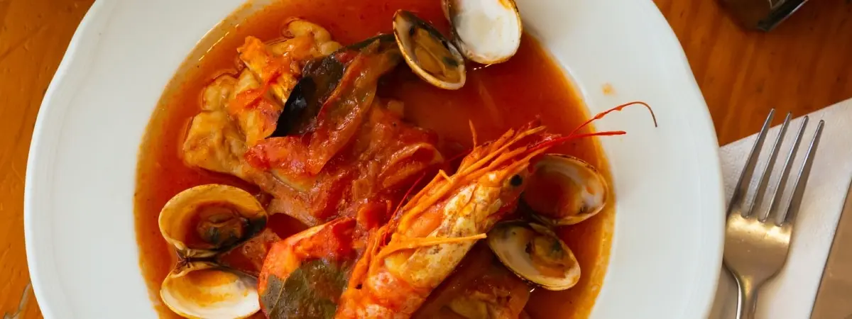 Plato de medallones de rape en salsa con almejas y langostinos. | Shutterstock