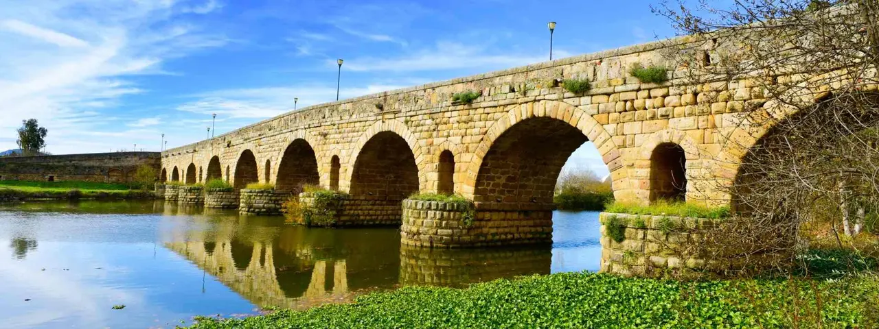 a view of the Puente Romano, an ancient Roman bridge over the Guadiana River, in Merida, Spain