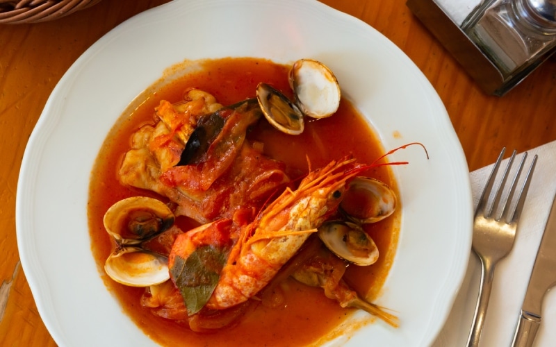 Plato de medallones de rape en salsa con almejas y langostinos. | Shutterstock