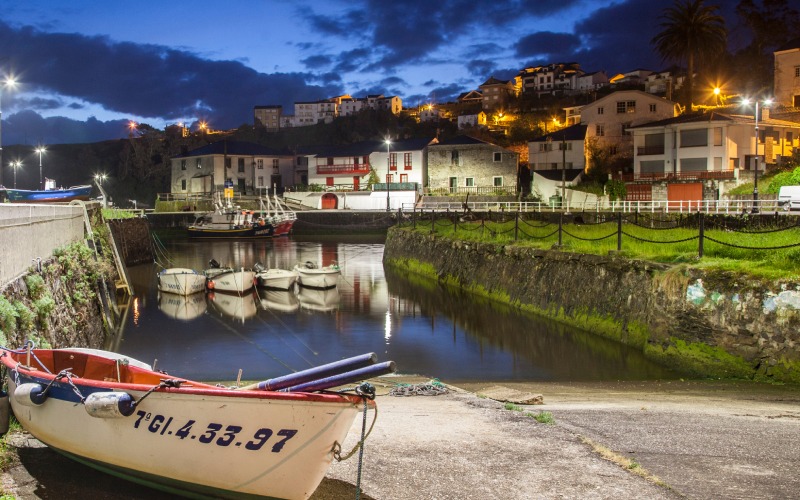 Vista nocturna del muelle de Puerto de Vega, con embarcaciones