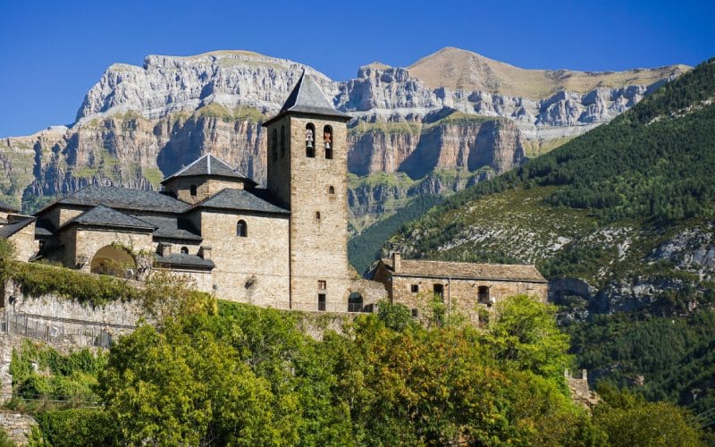 Una iglesia con una torre se alza en un paisaje montañoso