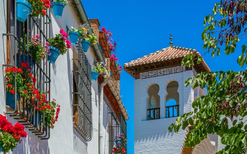 Una fachada blanca con flores y una torre