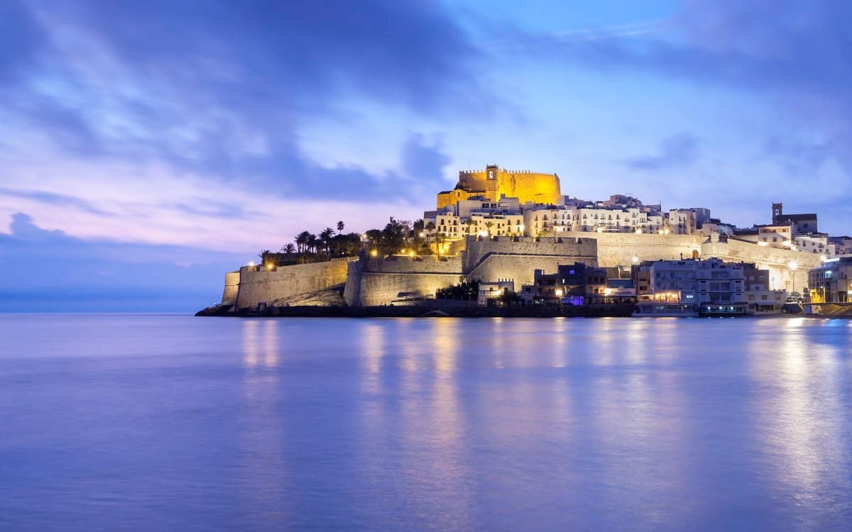 Panorámica de Peñíscola al amanecer, con el castillo iluminado en lo alto del peñón