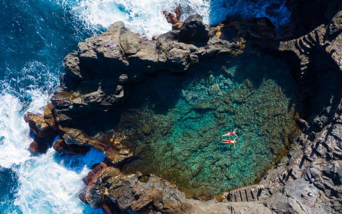Dos personas se bañan en una piscina natural.