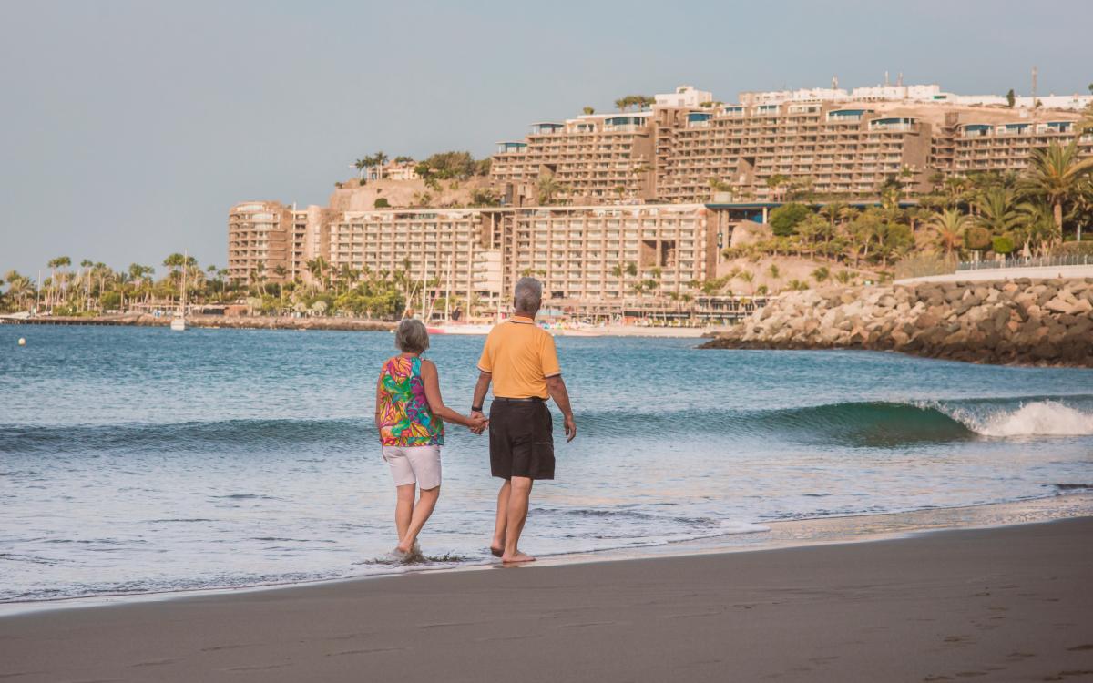 Turistas 'silver' pasean por la playa.