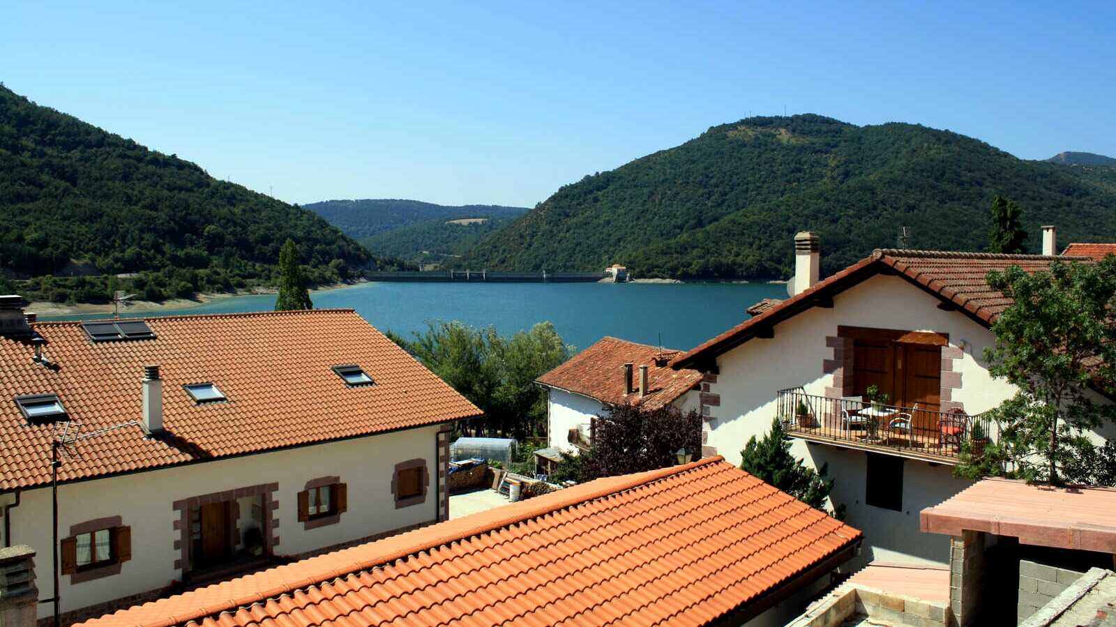 Tejados de Eugi sobre las aguas del embalse. | Dreamstime