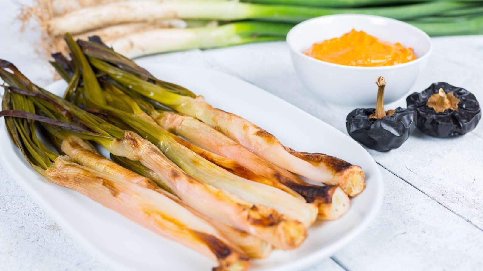 Calçots con salsa. | Shutterstock